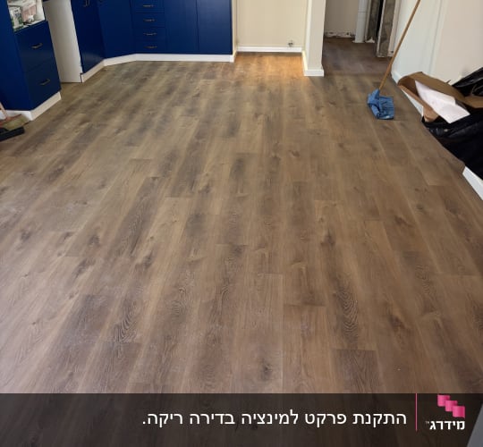 התקנת פרקט דמוי עץ עם פאנלים לבנים בחלל הסלון והמטבח